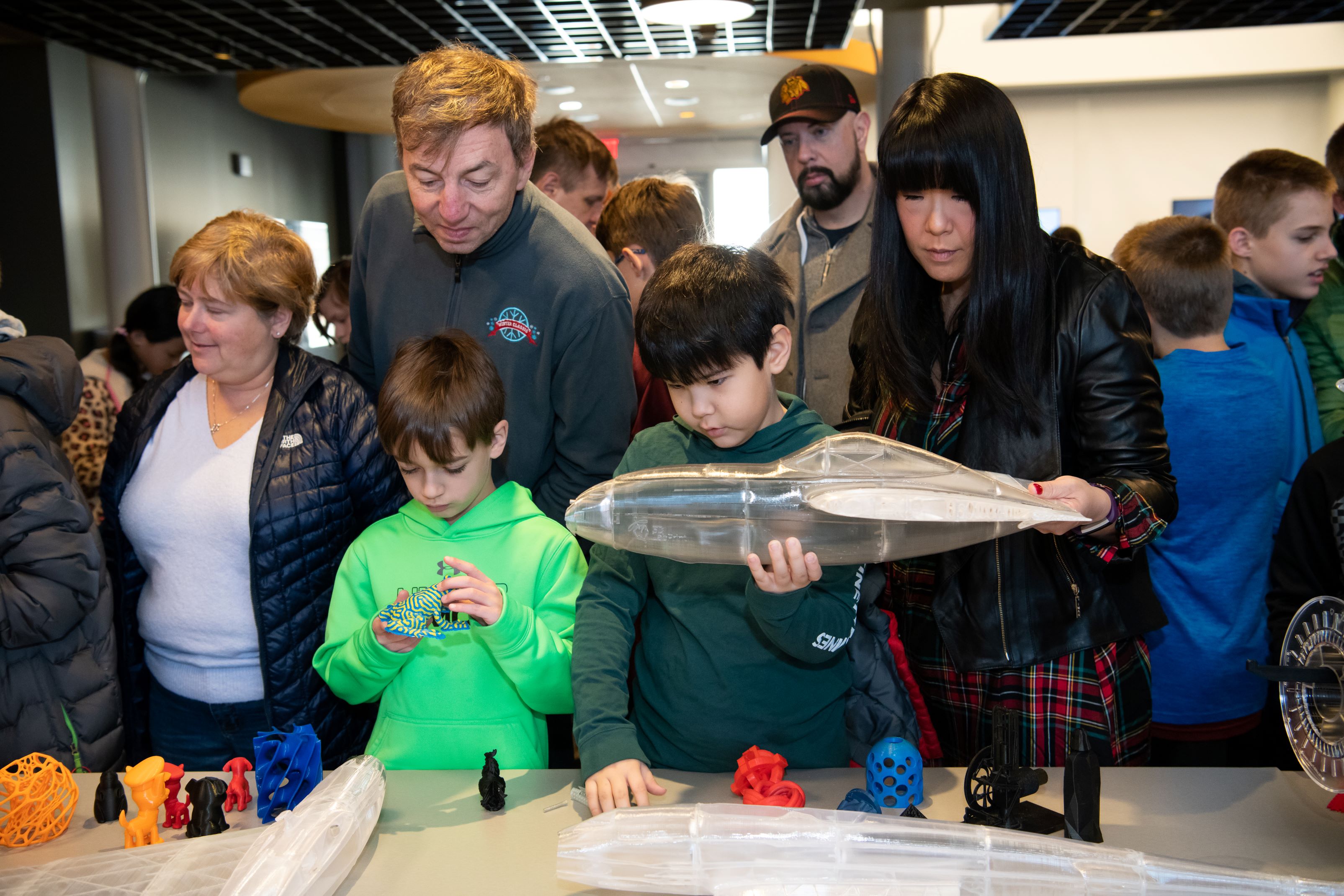 At the Science of 3D Printing show, children look and touch 3D-printed balls, and models of dogs and airplanes.